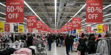 Shoppers excitedly browsing a retail store with large '60-90% off' banners during a 2025 clearance event
