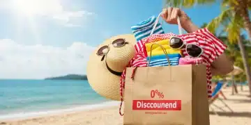 Woman happily holding a shopping bag with 55% off swimwear and beach accessories on a sunny beach, representing summer clearance 2025.